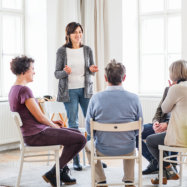 standing woman talking in front of the other people