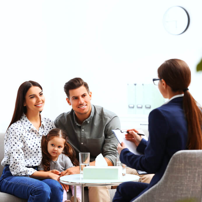 man and woman with their child looking at another woman with a clipboard